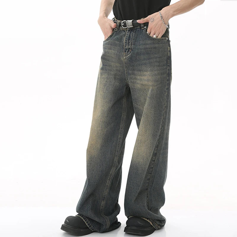old blue washed denim pants displayed on a model wearing casual attire with a belt