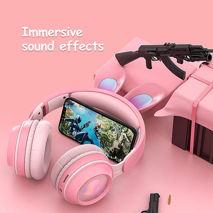 Pink rabbit ear wireless headphones with immersive sound effects, smartphone, and gaming accessories on a pink background.