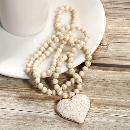 Vintage handmade knotted beaded necklace with heart-shaped mother pearl pendant in love white and blue. Bohemian style accessory.