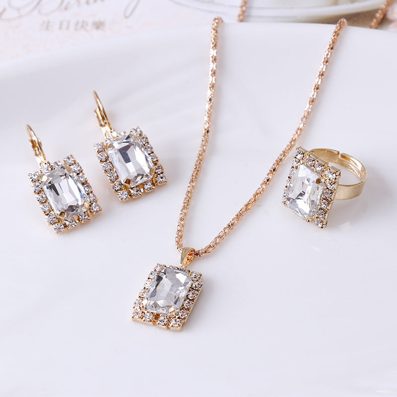 Elegant three-piece crystal jewelry set featuring necklace, earrings, and ring in gold alloy.