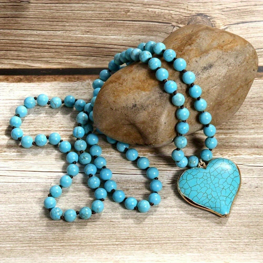 Vintage handmade beaded necklace featuring turquoise pearls and a heart-shaped pendant on a stone background.